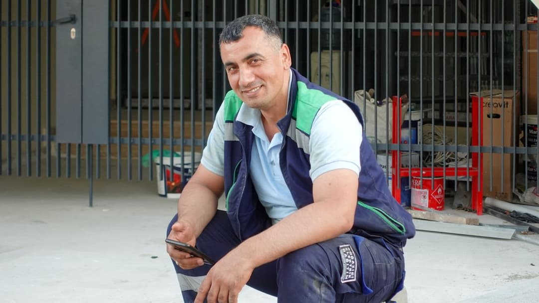 Trabajador de construcción sonriendo con su celular en obra